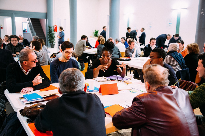 Viele Menschen,die miteinander diskutieren und rund um einen Tisch sitzen