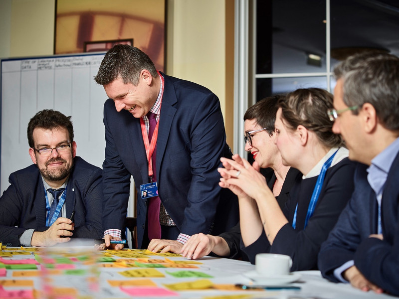 People in suits brainstorming, whilst sitting around a table